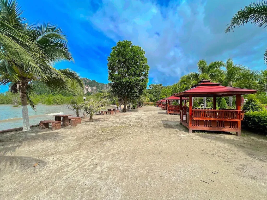 The sandy beach path with a sala and palms
