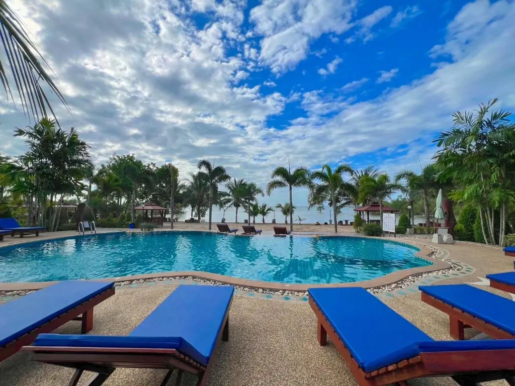 The pool and blue sun loungers under a wide sky