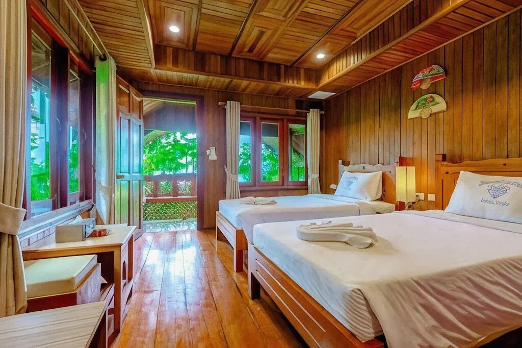 Twin beds in a teak-panelled Sea / Pool View Cottage