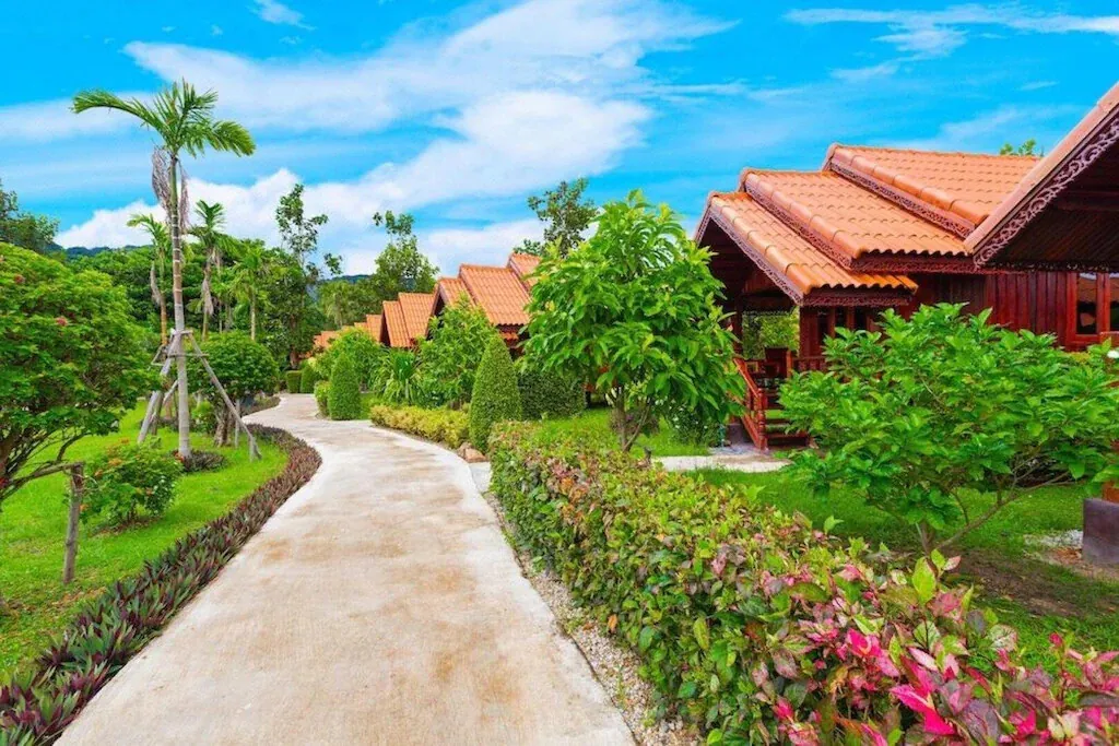 A garden walkway past terracotta-roofed cottages