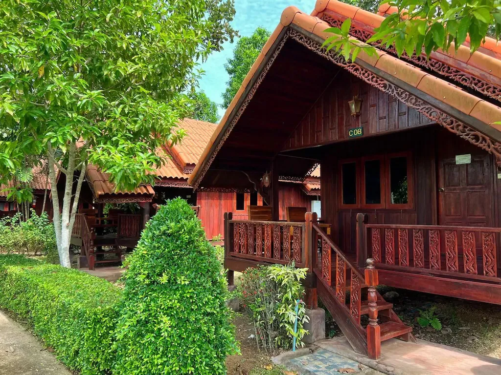 A wooden cottage with a carved balcony among the gardens
