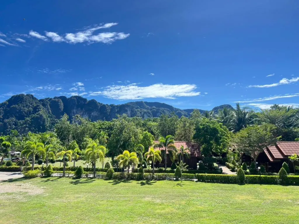 Lawns and wooden cottages beneath Krabi's limestone mountains