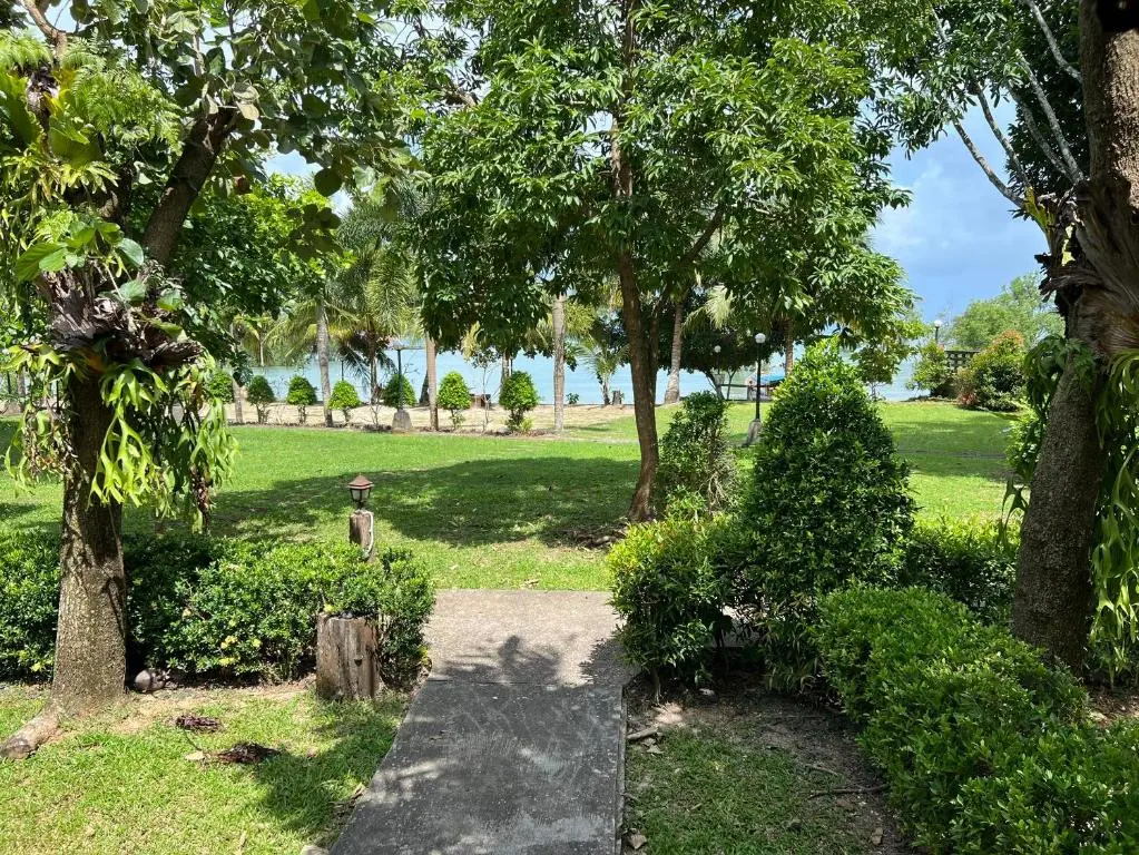 A shaded garden path leading towards the sea